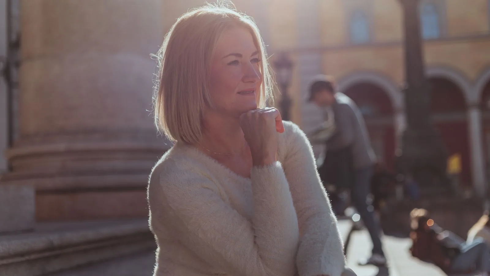 Frau um die fünfzig genießt entspannt einen sonnigen Tag in der Stadt